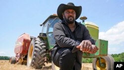 FILE - Farmer John Boyd Jr., poses for a portrait during a break from baling hay at his farm in Boydton, Va., May 27, 2021. 