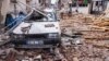 Cats sit in rubble front of a destroyed car at a damaged street after a 6.4-magnitude quake hit the Hatay province in southern Turkey, in Antakya, Feb. 21, 2023.