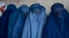 FILE - Afghan women wait to receive food rations distributed by a humanitarian aid group, in Kabul, Afghanistan, May 23, 2023. 