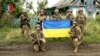 Ukrainian servicemen of the 35th Separate Brigade of Marines pose for a photograph with the Ukrainian flag in the liberated village of Storozheve, in Dontesk region, Ukraine, in the still image taken from a social media video released on June 12, 2023. 