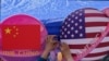 A vendor tights a flowers deco in between of the planets shaped of China and American flags on display at a store during a Spring Carnival in Beijing on May 13, 2023. (AP Photo/Andy Wong)