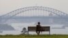 FILE - A man watches the sunset from a park bench in the Eastern suburbs of Sydney, Nov. 16, 2020. 