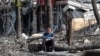 FILE - A man sits in a courtyard near a building damaged during the Ukraine-Russia conflict in the southern port city of Mariupol, Ukraine, April 25, 2022.