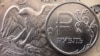 Una moneda de rublo ruso vista junto a billetes de dólares estadounidenses y una moneda de un dólar en Moscú, el 15 de marzo de 2022.
