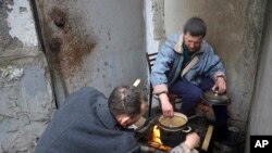 Los residentes de Mariúpol cocinan sentados en la entrada de su edificio de apartamentos dañado en un área de la ciudad que los separatistas respaldados por Rusia afirman controlar en la ciudad ucraniana de Mariúpol, el 13 de abril de 2022.