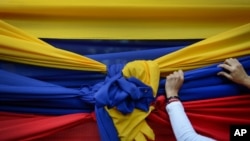 Una partidaria de la oposición sostiene una tela con los colores de la bandera venezolana antes de un mitin con el líder opositor Juan Guaidó en Caracas, Venezuela. Enero 11, 2020.