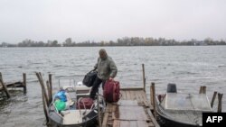 Un hombre sale de su casa hacia su residencia de verano en una isla en el río Dnipro después de un ataque a una reserva de petróleo en Kherson el 20 de noviembre de 2022, en medio de la invasión rusa de Ucrania.