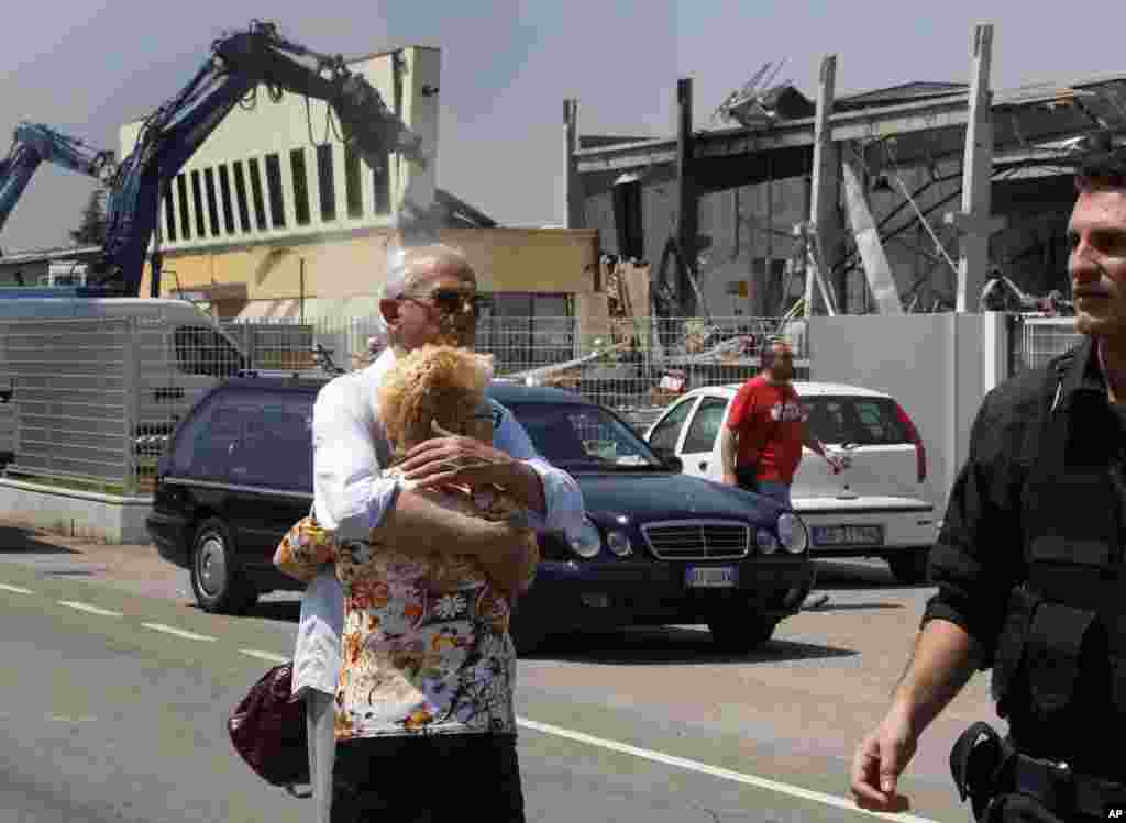 Un poblador de Mirandola de apellido Borghi, quien perdió a un hijo en el terremoto, trata de consolar a su esposa frente a la fábrica de molduras BBG que resultó destruida por el temblor en el norte de Italia este martes 29 de mayo d