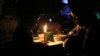 FILE - With electricity unavailable or unaffordable for many, Learnmore Mavhura, right, helps his 9-year old nephew, Lionel, do his homework by candlelight, in Harare, Zimbabwe, July 23, 2019.