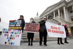 Manifestantes protestan frente al Capitolio de Estados Unidos, el viernes 31 de enero de 2020, en Washington mientras los senadores continuaban el juicio político contra el presidente Donald Trump.