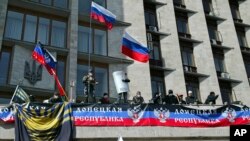 Activistas ondean banderas rusas y muestran un cartel llamando a la formación de la "República Donetsk".