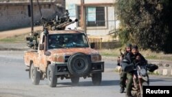Rebeldes liderados pelo grupo militante islâmico Hayat Tahrir al-Sham conduzem uma mota em al-Rashideen, província de Alepo, Síria, a 29 de novembro de 2024.
