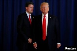 El Secretario de Personal de la Casa Blanca, Rob Porter (izquierda). recuerda al presidente Donald Trump que olvidó firmar una ley después que el mandatario se retirara rápidamente, luego de hacer declaraciones a periodistas en su campo de golf en Bedminster, Nueva Jersey. Aug.12, 2017.