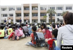 Estudiantes sentados en un patio de recreo después de ser evacuados del edificio escolar tras un terremoto en Ikeda, Osaka, oeste de Japan, el lunes, 18 de junio de 2018.