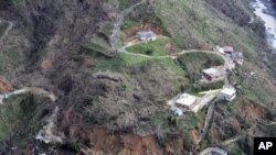This photo made available by the U.S. Coast Guard, shows homes near a washed out road in Utuado, Puerto Rico, Oct. 3, 2017. 
