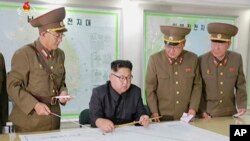 朝鲜官方电视台KRT的视频截图和画面显示朝鲜领导人正在听取情况介绍（2017年8月）