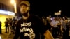 A man is moved by a line of police as authorities disperse a protest in Ferguson, Mo., Aug. 20, 2014.