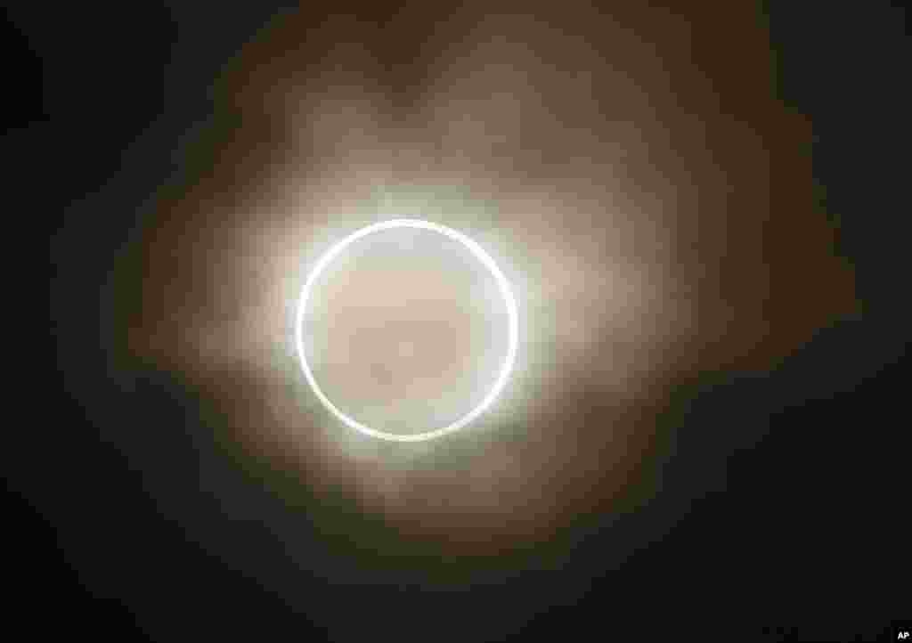 La luna se desliza a trav&eacute;s del sol, mostrando un halo resplandeciente de luz, durante un eclipse anular. Vista desde un parque junto al mar en Yokohama, Jap&oacute;n.