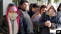 Inmigrantes indocumentados desafían el frío haciendo linea para obtener su licencia de conducir de California, en Stanton, California.