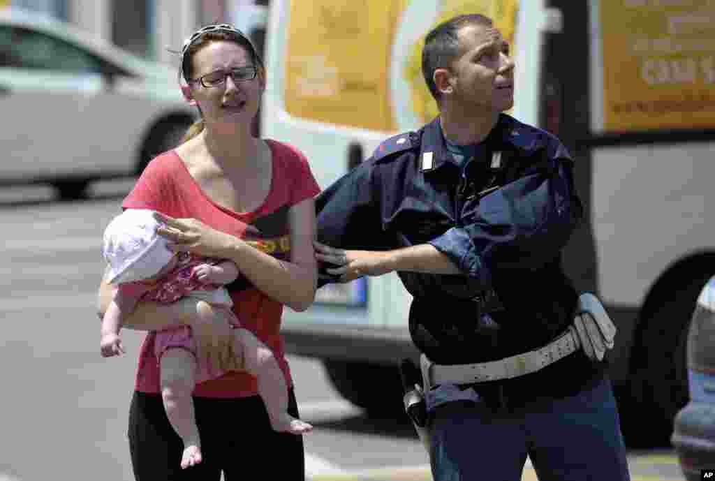 Un policía italiano ayuda a una mujer que carga a su bebé durante el temblor y las réplicas que afectaron severamente la ciudad de Mirandola.