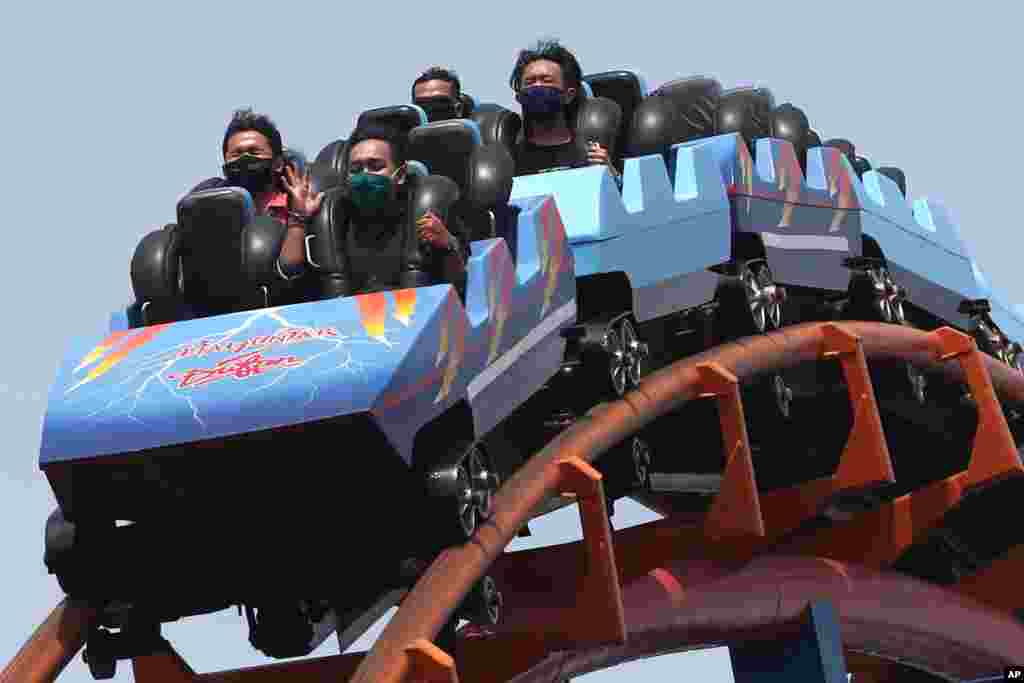 Hombres indonesios que llevan m&#225;scaras protectoras y se sientan separados mientras disfrutan de un paseo en el parque de atracciones Dunia Fantasi en el primer d&#237;a de reapertura luego de semanas de cierre debido a las restricciones del coronavirus.