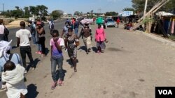 Abanye abantu bayazihambela bengagqokanga ama masks avimba ukumemetheka komkhuhlane weCoronavirus COVID-19. (Columbus Mavhunga/VOA)