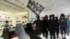 香港黑衣抗議者在銅鑼灣的一個商場裡舉“光復香港，時代革命”的旗子示威。（2019年12月26日）