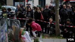 Una niña deja un ramo de flores en honor de las víctimas de los ataques de París.