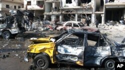 Ciudadanos sirios observan el lugar donde dos bombas explotaron en el barrio progubernamental de Zahraa, en Homs, Siria, el domingo, 21 de febrero de 2016.
