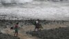 ARCHIVO - Los surfistas caminan por el agua en la playa de El Tunco en Tamanique, El Salvador.Agosto 1 de 2017.