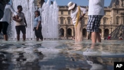People cool off next to the fountains at Louvre Museum in Paris, France, July 24, 2019. 