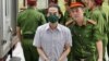 Vietnam's former deputy minister of foreign affairs To Anh Dung is led into court by police for sentencing during the repatriation flight trial in Hanoi on July 28, 2023. (Photo by Anh TUC / AFP)