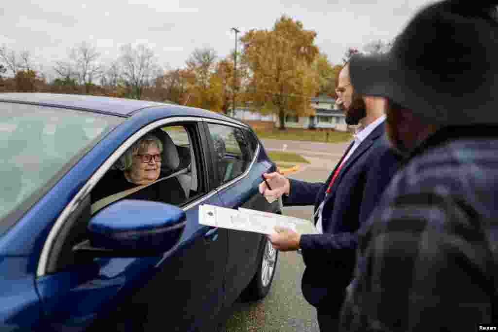 Funcionários eleitorais Owen O&#39;Keefe e Brandon Rieckhoff ajudam Mary Miller, com problemas de mobilidade, no processo de votação à porta da Faith Lutheran Church em Grand Rapids, Michigan, a 5 de novembro de 2024.