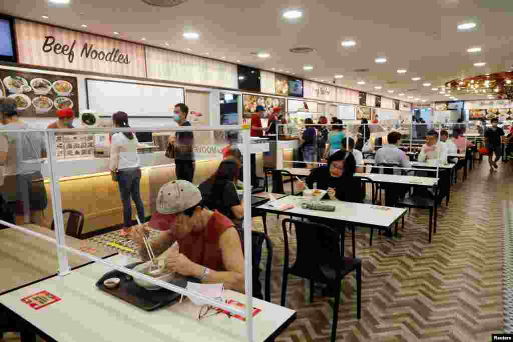 Clientes comen en una mesa instalada con divisores de plexigl&#225;s en un patio de comidas en Singapur cuando la ciudad estado reabre su econom&#237;a en medio del brote de la enfermedad del coronavirus (COVID-19).