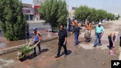 Iraqi municipality workers clean the scene of a suicide attack in Baghdad's western Eskan neighborhood, Iraq, Sunday, Sept. 25, 2016. A suicide bomber killed several people who were setting up tents on Sunday ahead of a major Shi'ite religious observance next month, officials said. 