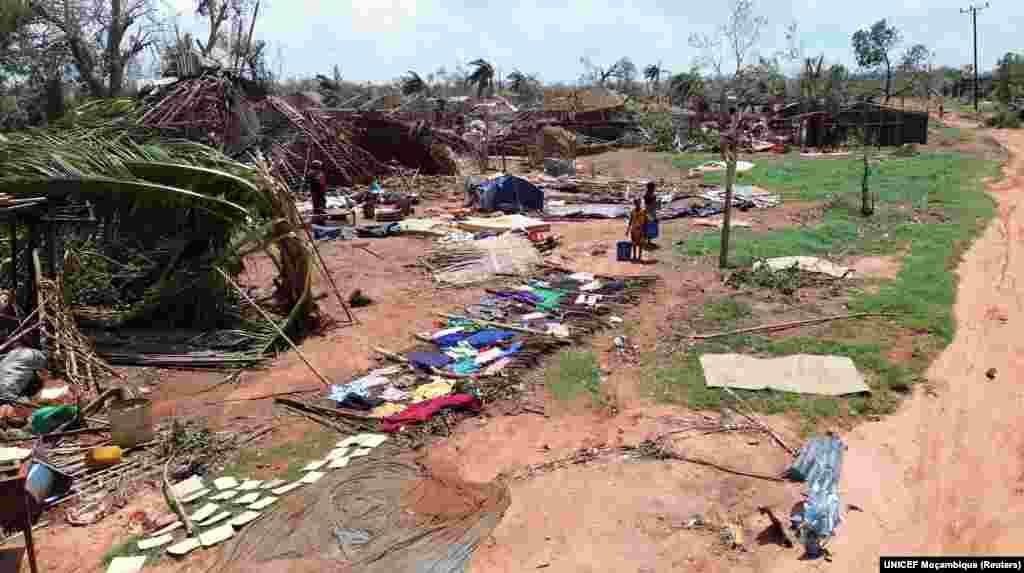 Pessoas de pé no meio de edifícios destruídos, árvores desenraizadas e destroços após o ciclone Chido ter atingido Moçambique, no distrito de Mecufi, província de Cabo Delgado, Moçambique, a 16 de dezembro de 2024, nesta captura de ecrã retirada de um vídeo de um drone.