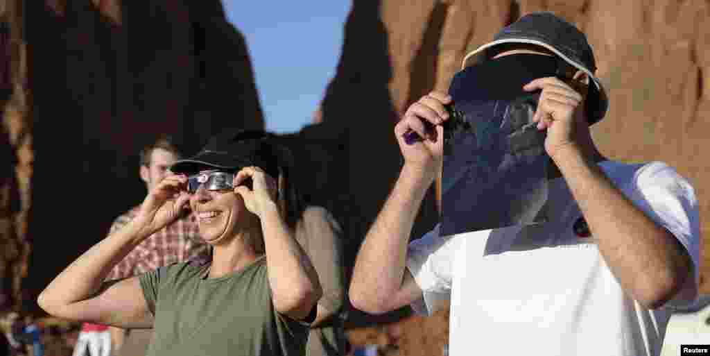 Turistas miran a trav&eacute;s de gafas protectoras el eclipse anular desde el Parque Valley Tribal Park en Utah.