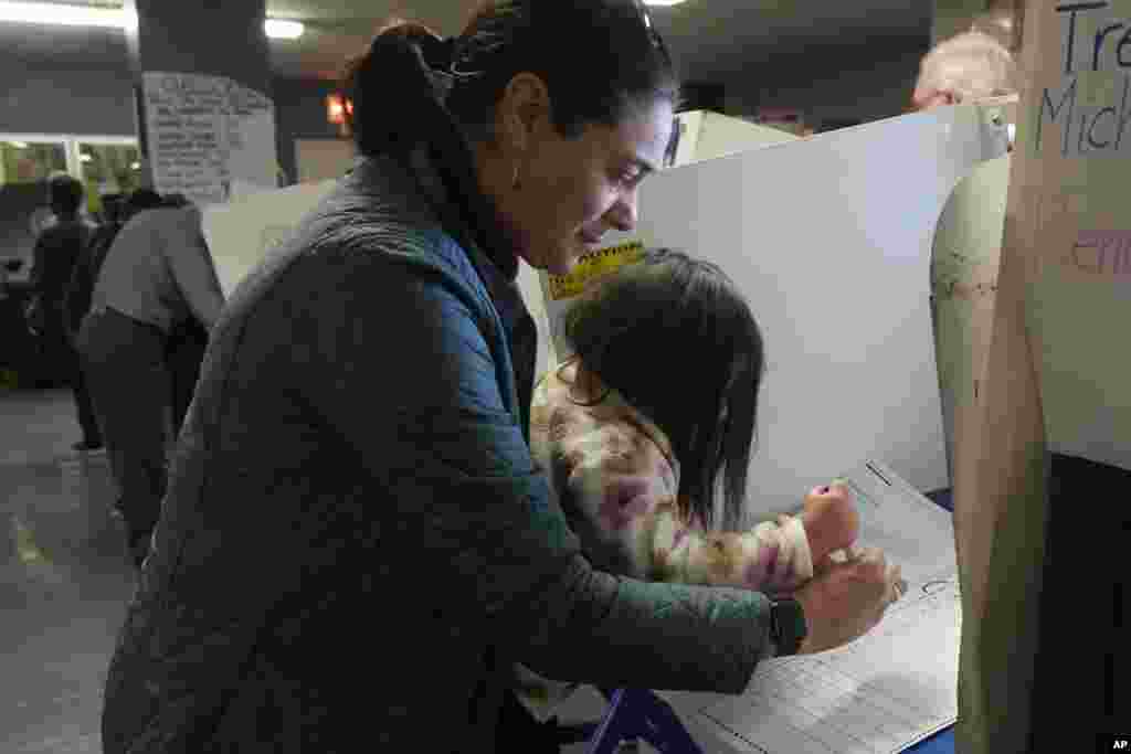 Vesta Avery, 2 anos, ajuda a sua mãe Alexis Taylor a votar na Escola Mickey Mantle, em Nova Iorque, a 5 de novembro de 2024.