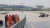 South Korean emergency workers search for survivors on a flooded road leading to an underground tunnel where some 19 cars were trapped by flood waters after heavy rains in Cheongju on July 15, 2023.