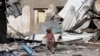 Un niño palestino pasa junto a edificaciones destruidas durante el bombardeo israelí de la Franja de Gaza en Deir al Balah el sábado 13 de enero de 2024.